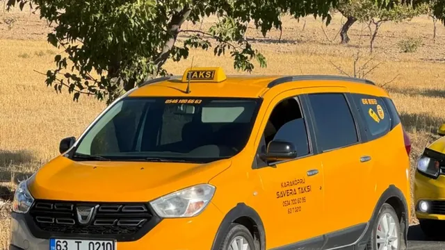 Karaköprü yolunda gündüz ilerleyen sarı taksi