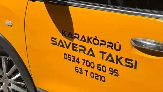 Üzerinde iletişim bilgileri görünen sarı taksinin yan kapısı